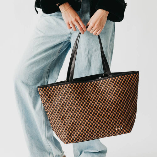 Person holding a woven patterned handbag against a light background